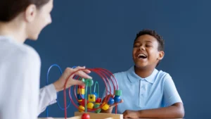 Smiling child engaged in an aba therapy session using educational toys with a therapist in a supportive environment