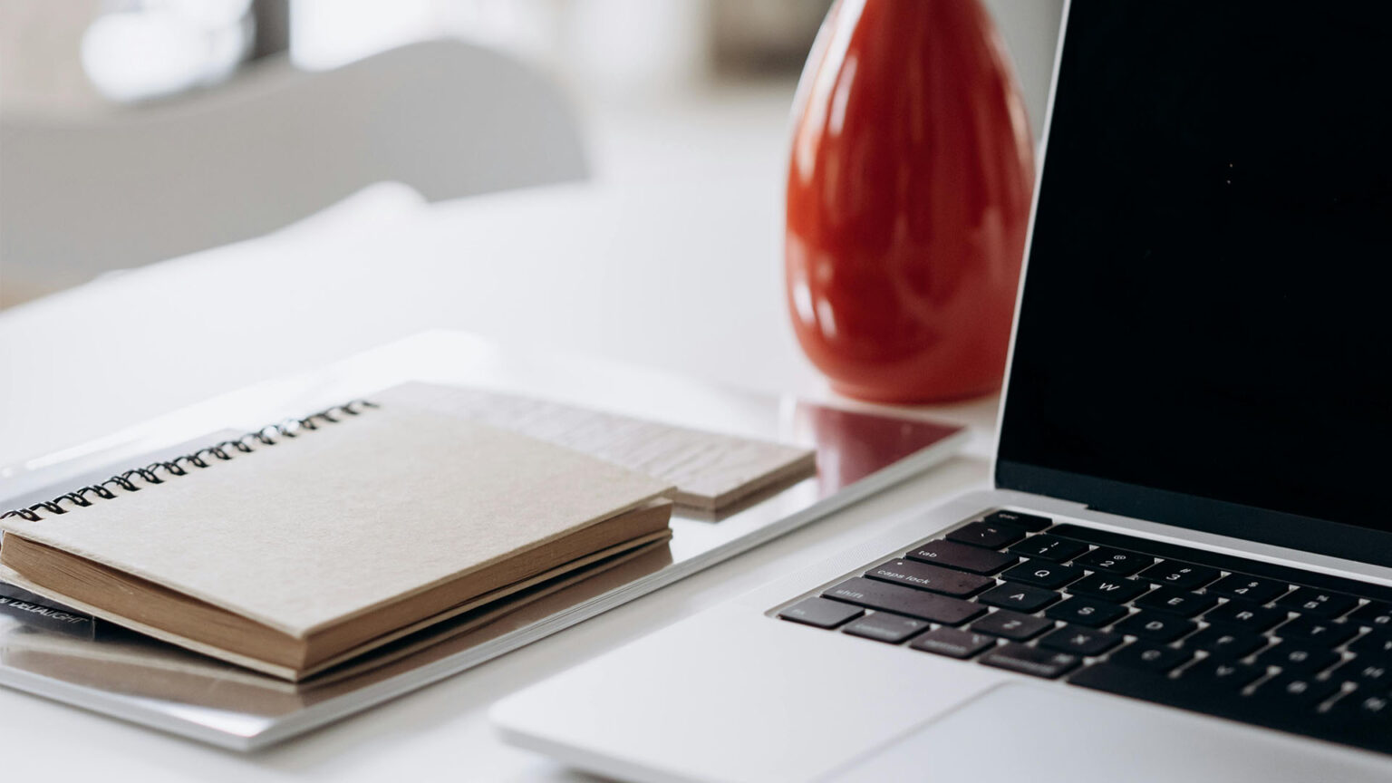 Minimalist workspace with laptop and notebook used for invoice management