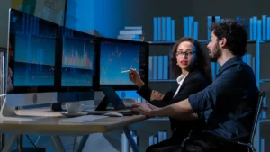 Professionals analyzing data charts on multiple monitors in a data mining session