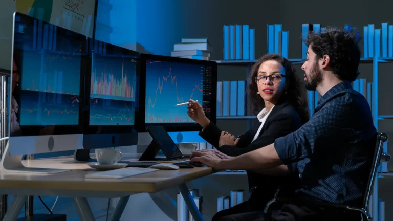 Professionals analyzing data charts on multiple monitors in a data mining session
