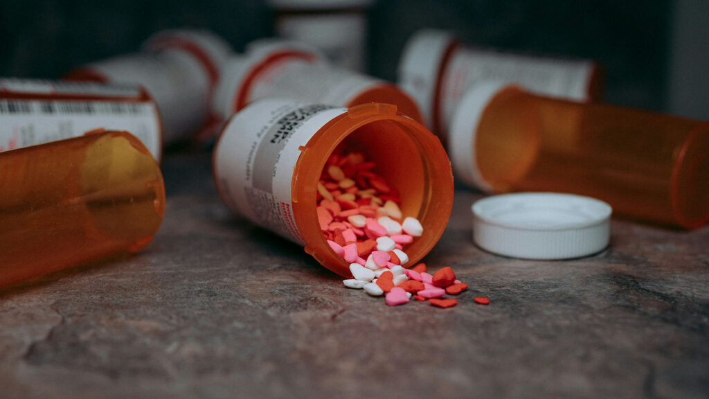 Prescription pill bottle spilling colorful heart shaped tablets