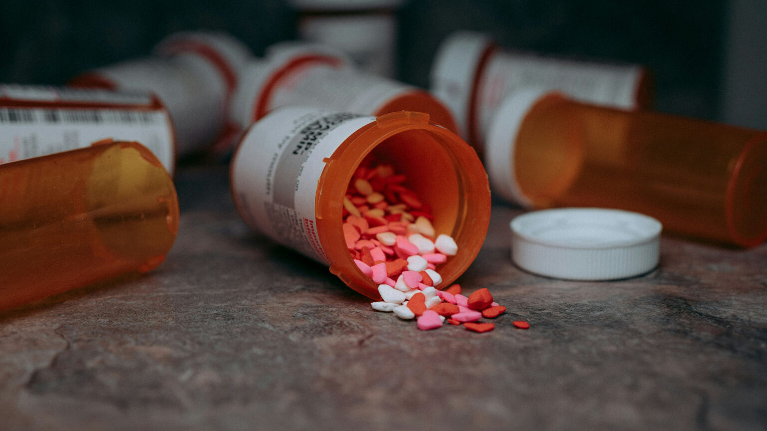 Prescription pill bottle spilling colorful heart shaped tablets
