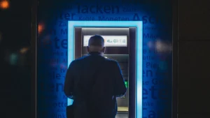 Man using atm at night with glowing blue light