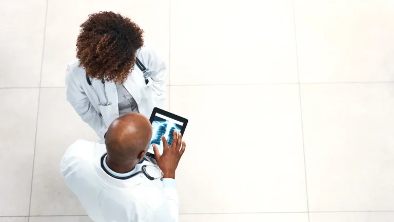 Two doctors reviewing an X-ray image on a tablet, discussing healthcare strategy