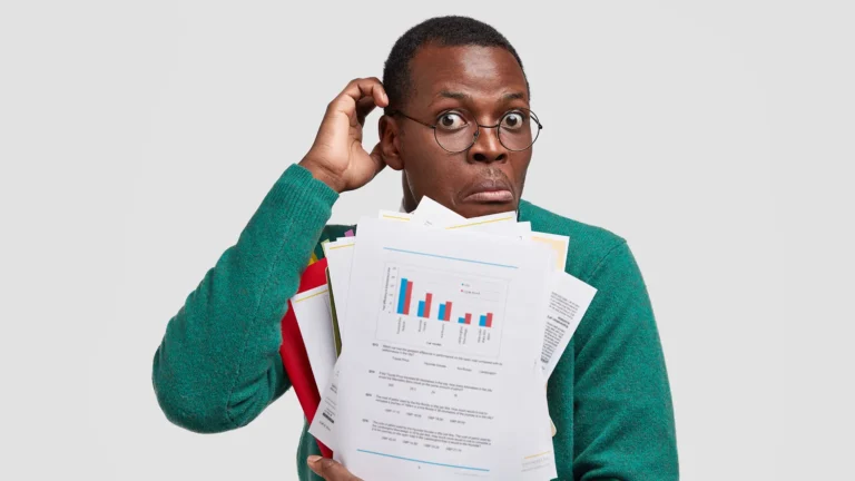 Confused businessman holding paperwork and charts with a surprised expression