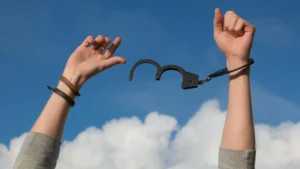 Hands breaking free from handcuffs under blue sky symbolizing financial freedom