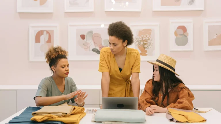 Three executives discussing business strategy with fabrics and a laptop