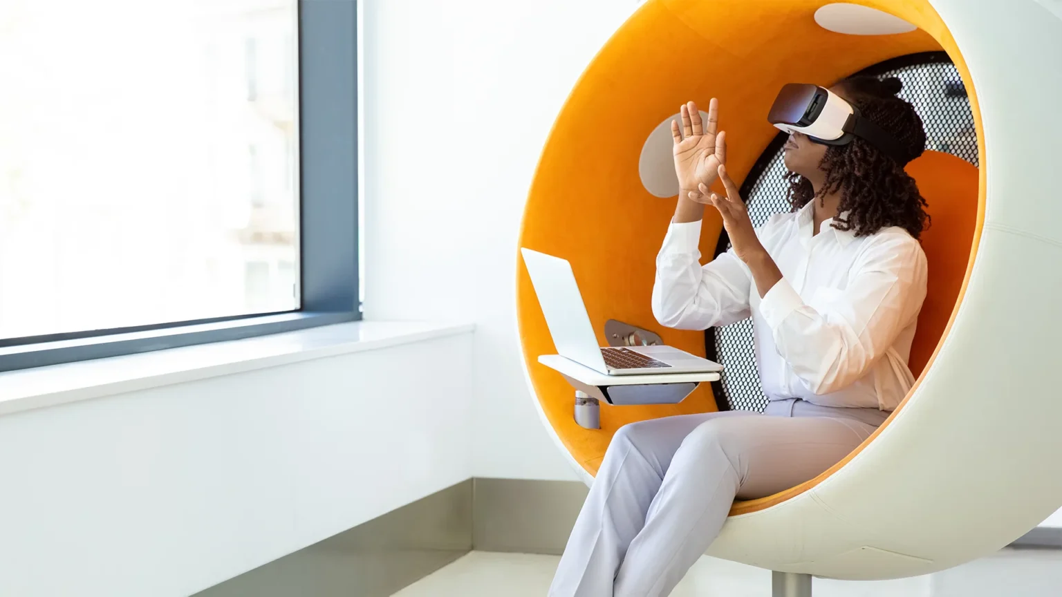 Woman using vr headset with laptop in a modern workspace