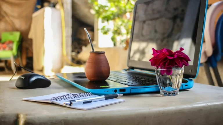 Laptop with notebook pen and flower in a cozy remote workspace setup