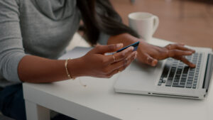 Woman holding a credit card while shopping online with a laptop