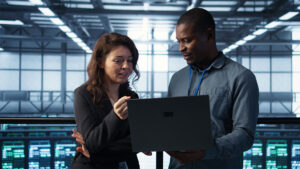Engineers reviewing a laptop in a modern data center managing servers
