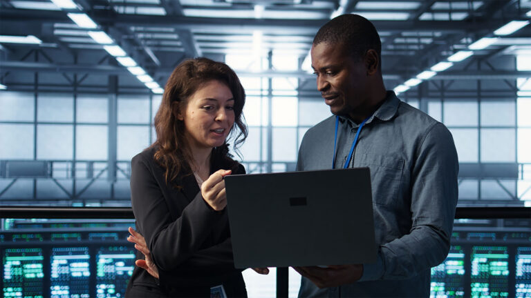 Engineers reviewing a laptop in a modern data center managing servers