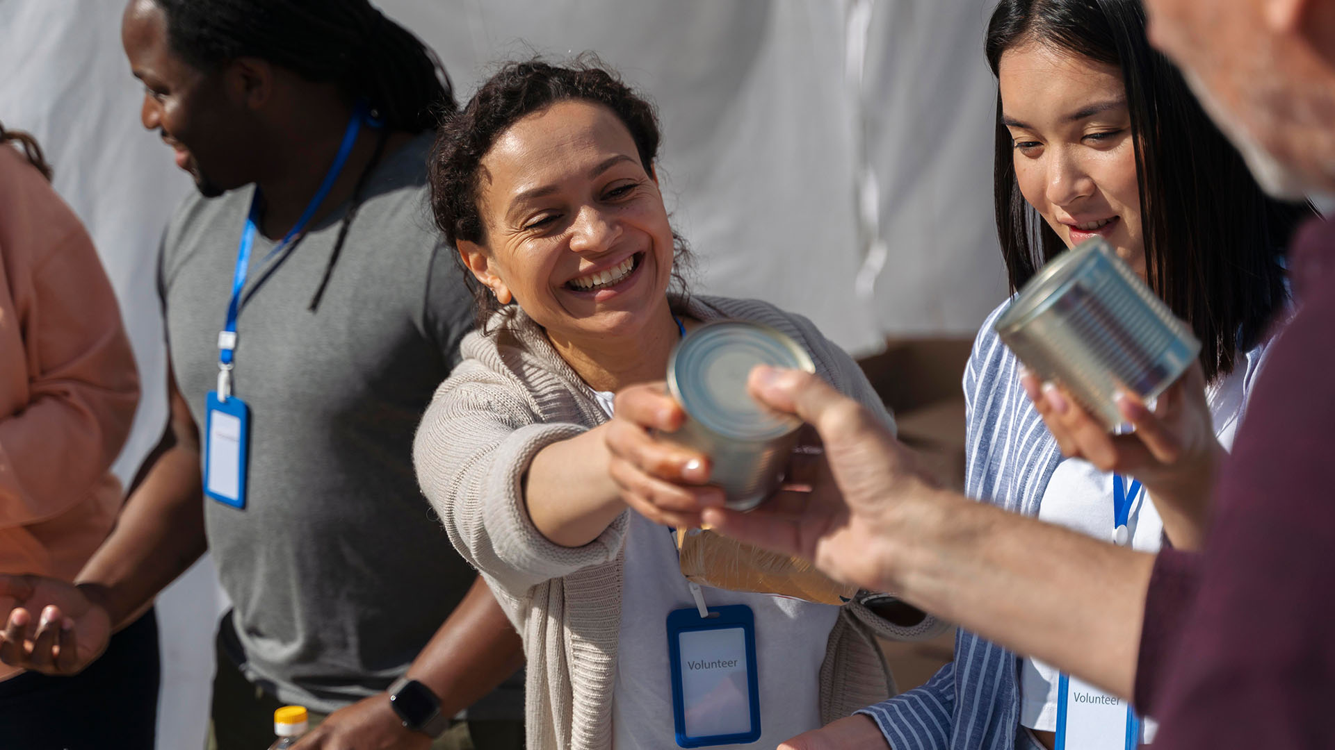 Smiling volunteers handing out canned food during a community support program
