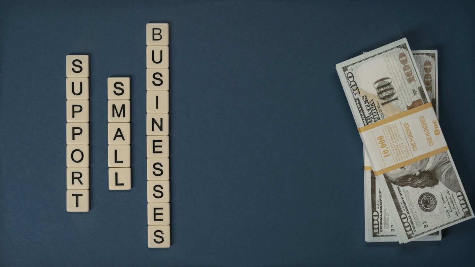 Support small businesses text with stack of dollar bills