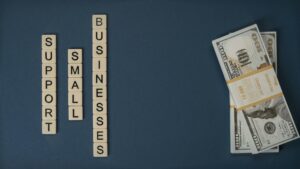 Support small businesses text with stack of dollar bills