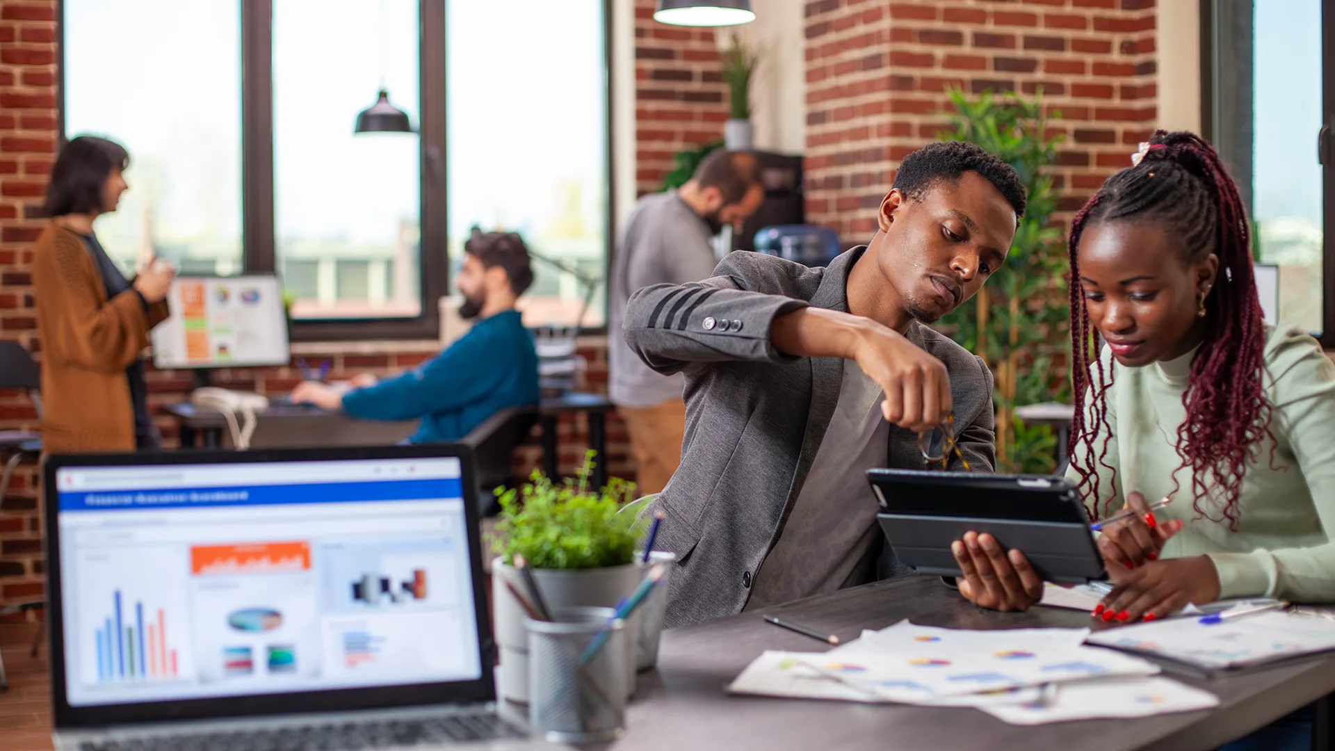 Diverse creative team collaborating in an open office using digital tablets