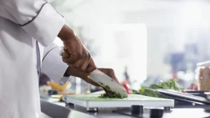 Chef chopping herbs on a cutting board in a professional kitchen
