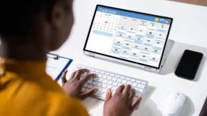 A person using an online calendar app to plan and schedule tasks on a laptop