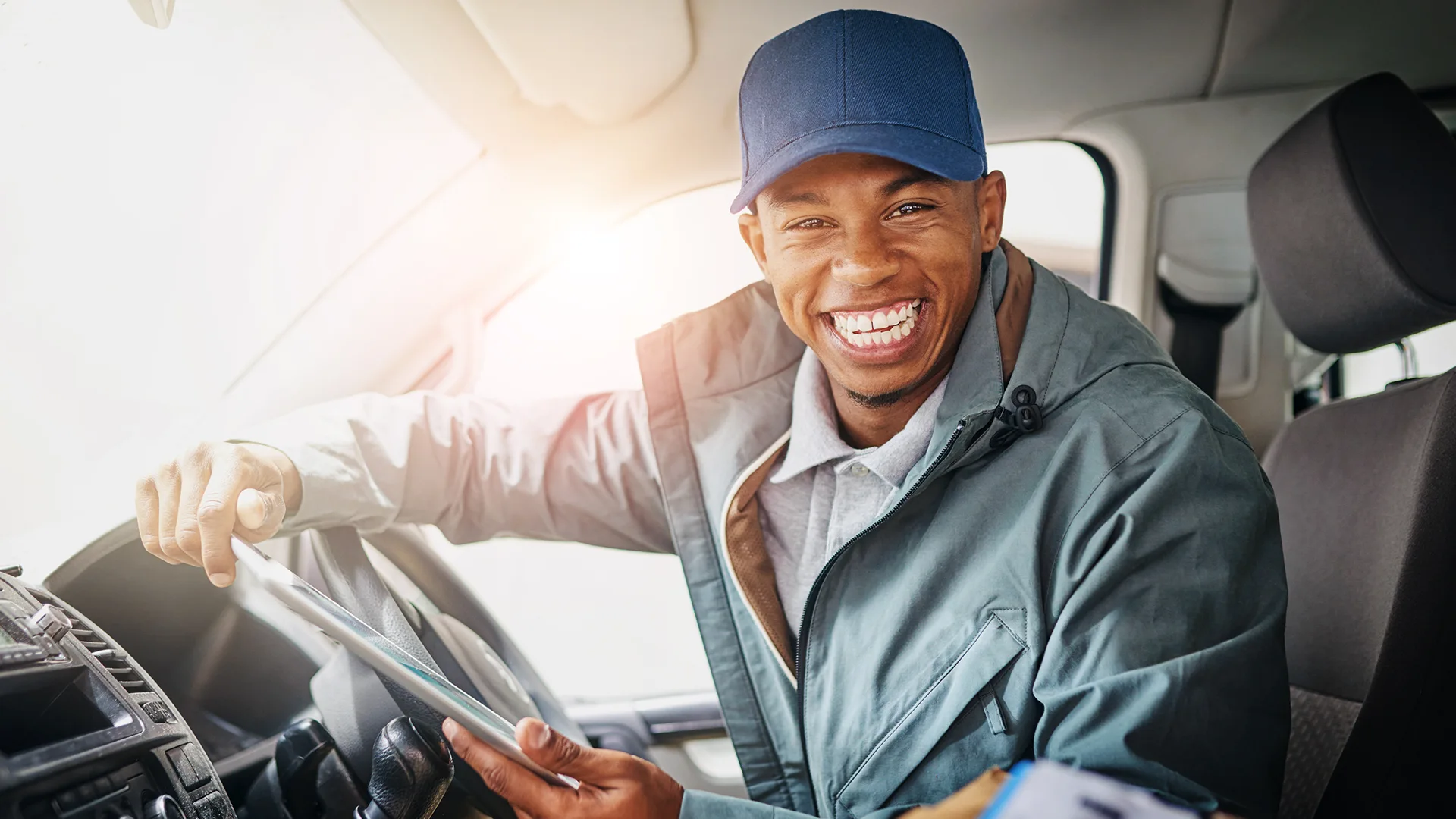 Smiling driver holding a tablet inside vehicle cabin