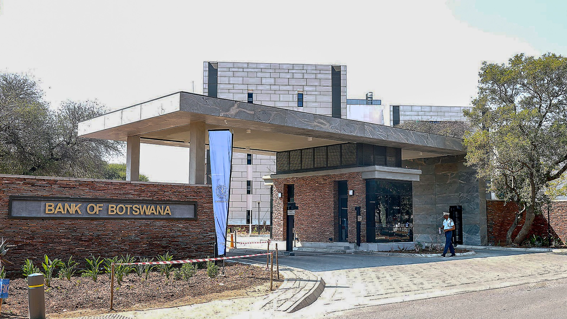 Entrance of the bank of botswana headquarters with security personnel and modern office buildings in the background