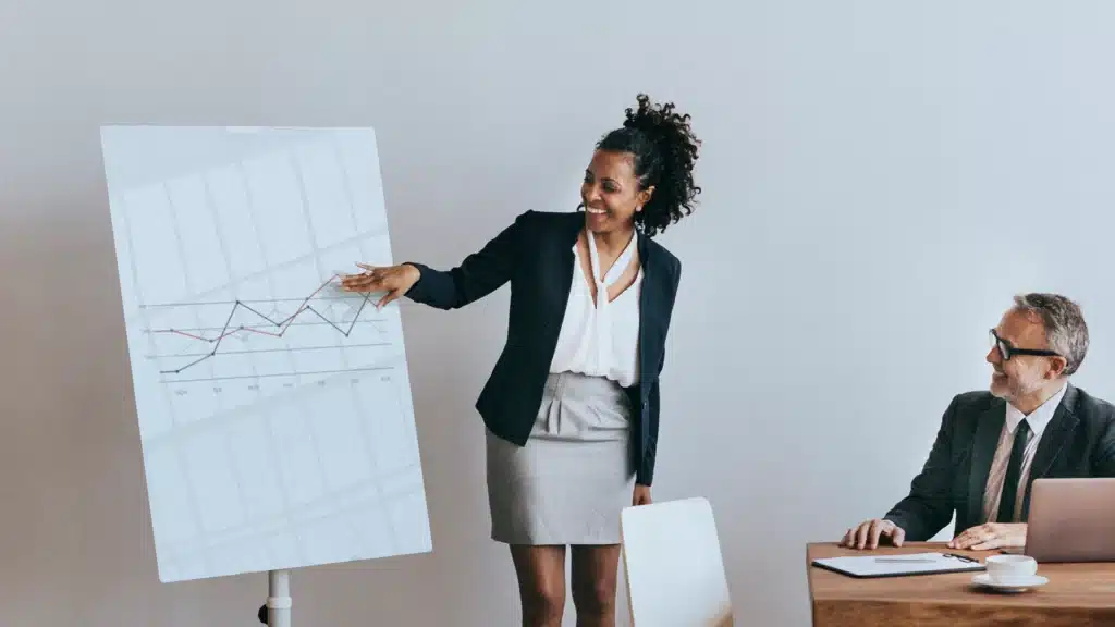 Businesswoman presenting data on a chart to colleagues during a meeting in a modern office