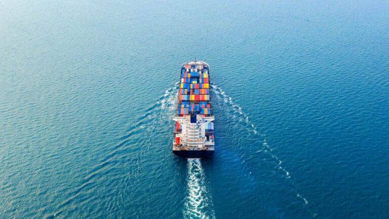 Aerial view of a cargo ship carrying colorful containers across the ocean