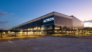 Altron headquarters building at dusk with illuminated signage and parked vehicles in front