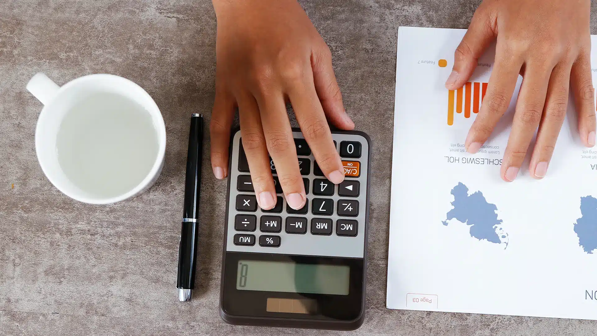 Person using a calculator and reviewing financial charts while planning investments and sip contributions on a desk