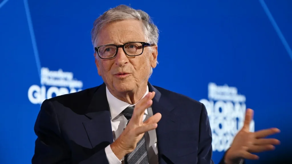 Bill Gates Speaking at a Global Economic Forum | Brimco Bill gates speaking at a global business forum against a blue background gesturing with his hands while addressing the audience