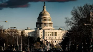 The u S Capitol building viewed from pennsylvania avenue with cars and pedestrians in the foreground