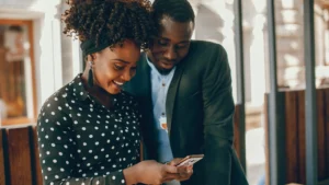 Smiling couple standing together and looking at a smartphone screen