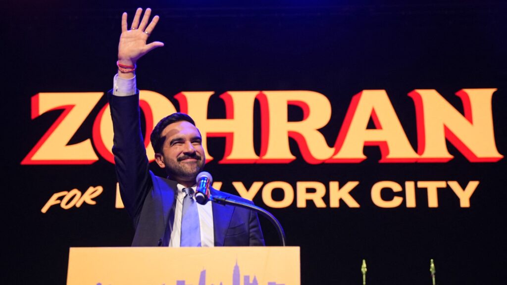 Zohran Kwame Mamdanis Victory Night in New York City | Brimco Zohran kwame mamdani celebrating election victory on stage in new york city waving to supporters with a smile