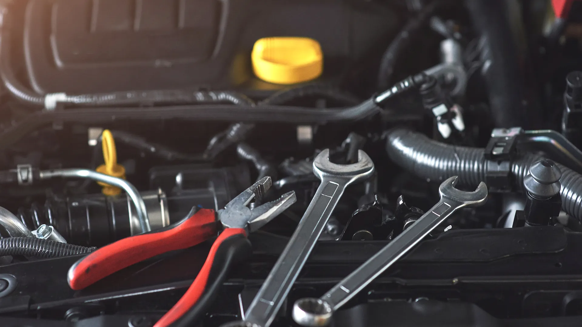 Close up of automotive tools and wrenches placed on a car engine during vehicle maintenance