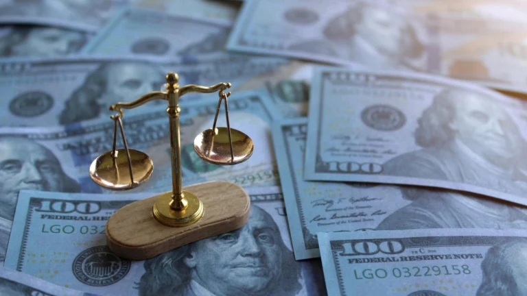 A small golden balance scale placed on scattered US dollar banknotes.