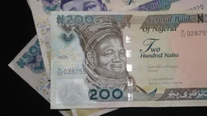 A close up photo showing nigerian ₦200 and ₦500 banknotes stacked on a dark surface