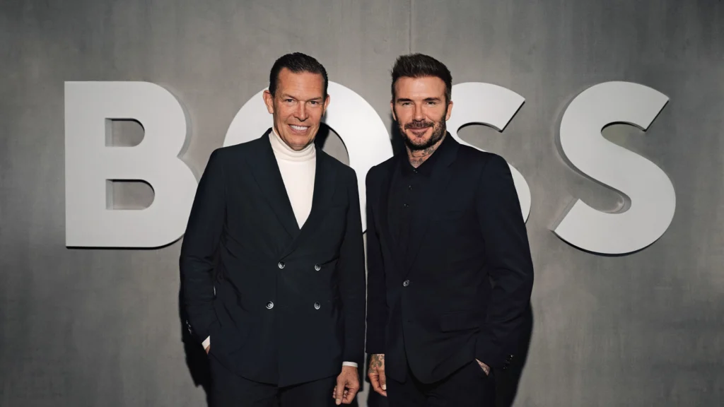 Daniel Grieder and David Beckham at a Hugo Boss Partnership Event | Brimco Daniel grieder ceo of hugo boss and david beckham pose in dark suits in front of a large hugo boss logo at a branded event backdrop