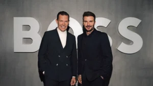 Daniel grieder ceo of hugo boss and david beckham pose in dark suits in front of a large hugo boss logo at a branded event backdrop