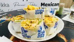 Plated wraps from sefalana bake  grill branded wings  things filled with grilled chicken lettuce and toppings displayed on a counter menu backdrop