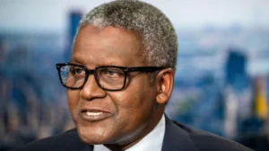 Portrait of aliko dangote wearing glasses speaking during an interview with a blurred cityscape in the background