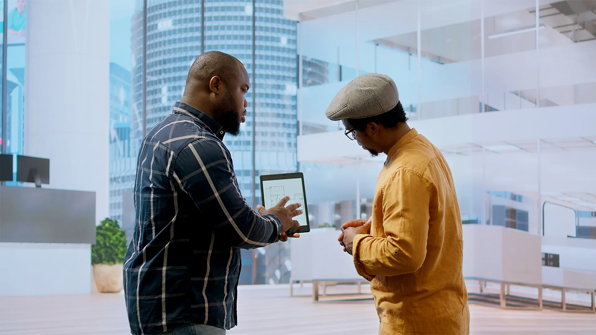 Real Estate Professionals Using Property Management Software | Brimco Two real estate professionals reviewing property floor plans on a tablet in a modern office building